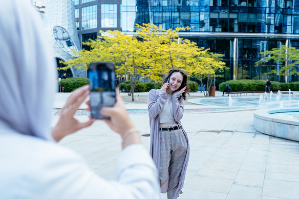 年轻女性在现代商业区摆姿势拍摄手机照片图片下载