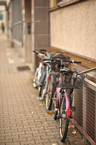 街道上的自行车 这张照片展示了三辆自行车停放在建筑物墙边的人行道上。图片下载