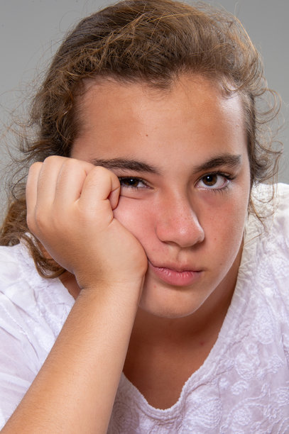 无聊的少女在灰色背景下看着镜头的头像照图片下载