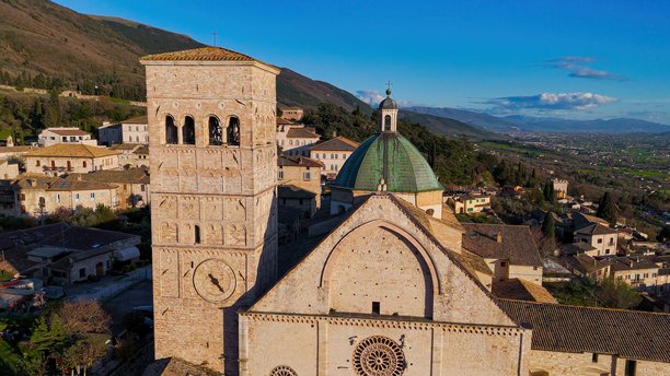 意大利翁布里亚大区阿西西的圣鲁菲诺大教堂鸟瞰图，展示了罗曼式建筑、钟楼和背景中的绿色山谷，历史悠久的教堂和灵性旅行的照片内容。图片下载