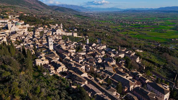 意大利翁布里亚地区阿西西历史中心及周围绿色山谷的鸟瞰图，清晰可见的教堂和钟楼，传统意大利小镇和文化旅游照片内容图片下载