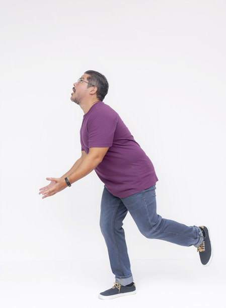 侧面视角的中年男子在奔跑中试图抓住掉落的物体，抬头期待着它会落在哪里。全身照片，背景为白色。图片下载