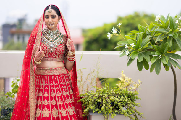 非常美丽的年轻印度新娘在户外穿着奢华的婚礼服装，化着妆，佩戴着华丽的珠宝的肖像照片图片下载