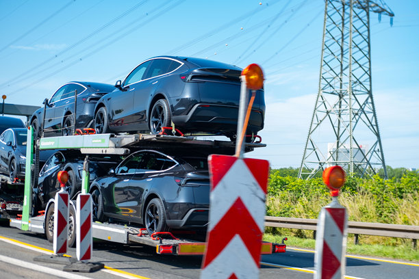运输拖车上装载着全新的深灰色特斯拉Model Y电动车，电动车交付，现代汽车工程，将汽车从工厂运送到经销商或客户，德国图片下载