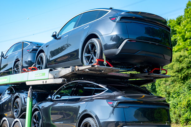 运输拖车上载有全新深灰色特斯拉Model Y电动车，电动车交付，现代汽车工程，将汽车从工厂运送到经销商或客户，德国图片下载