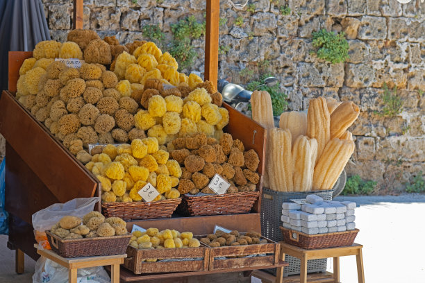 一个色彩斑斓的市场摊位，摆满了天然海绵，位于希腊罗德岛热闹的街道上。非常适合以地中海文化、手工艺和海滨旅游为主题的视觉素材。图片下载