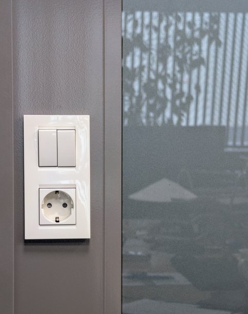 现代灰色办公室墙壁上的白色开关和电源插座特写照片图片下载