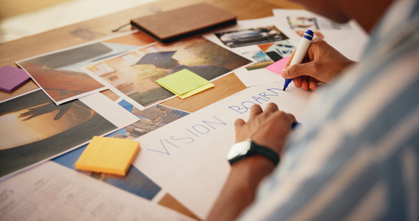在家中规划和书写愿景板的手，进行成长活动、愿望设计和显化。海报、人物和灵感图片用于激励、进度跟踪和个人发展。图片下载
