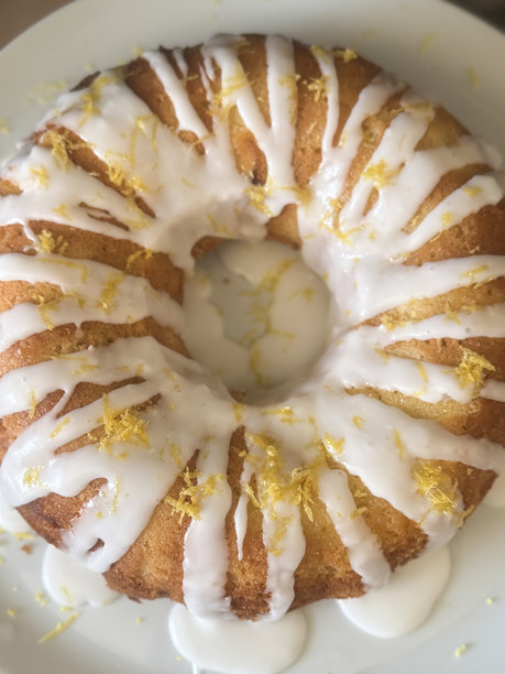 环形蛋糕模具中的柠檬糖霜蛋糕俯视图，糖霜滴落并装饰有柠檬皮碎片 / 自制烘焙图片下载