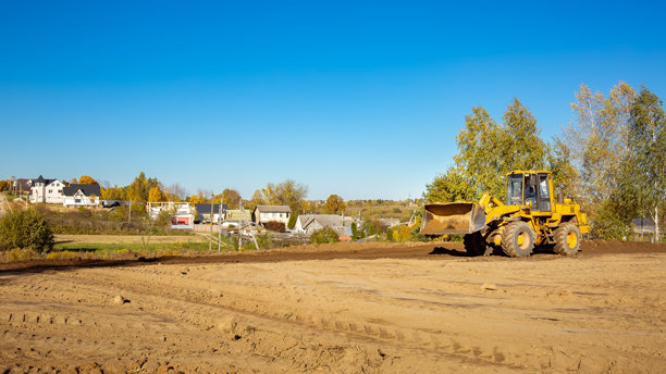 建筑工地上的黄色推土机。侧面视角的大轮挖掘机正在平整和清理土地。移动土方。留白空间。建筑区域。特种运输。高质量照片。图片下载