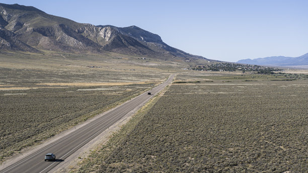 大盆地公路穿越内华达沙漠。空中视角下，一辆孤独的汽车在怀特派恩县的山地景观中行驶。图片下载