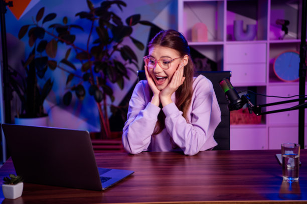 受欢迎的女性博主在时尚的工作室环境中兴奋地与观众互动，进行晚间直播。图片下载
