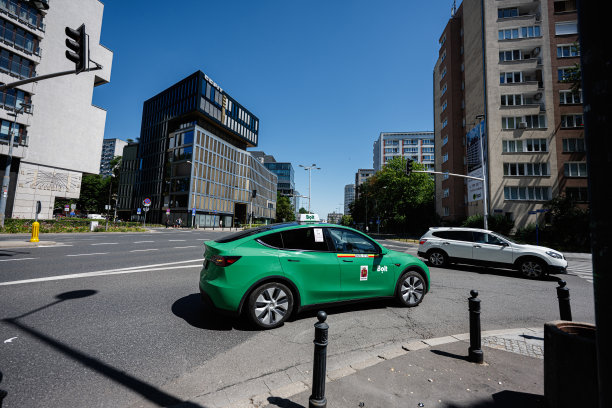 华沙，波兰阳光明媚的街道交叉口停放着一辆绿色闪电租赁的特斯拉Model Y汽车图片下载