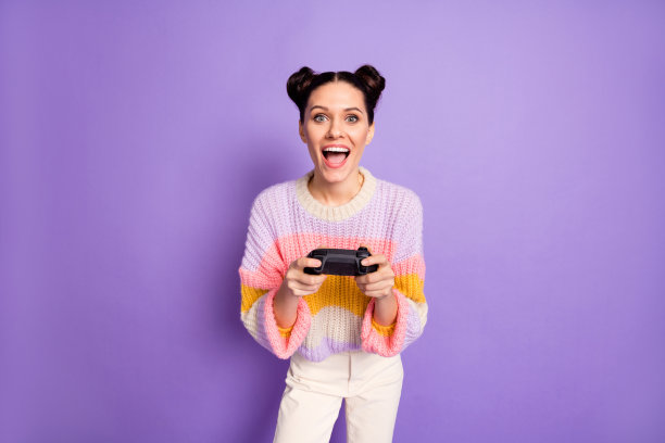 快乐、兴奋、疯狂的微笑女性在紫色背景下沉迷于玩PlayStation视频游戏的照片图片下载