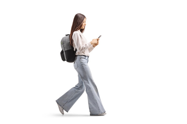 一名女性青少年全身侧面走路并查看手机的照片图片下载