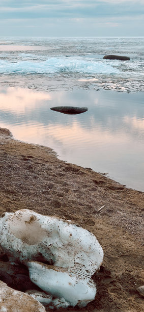 宁静的冰块在日落时分映照在平静的海洋水面上。竖版照片图片下载