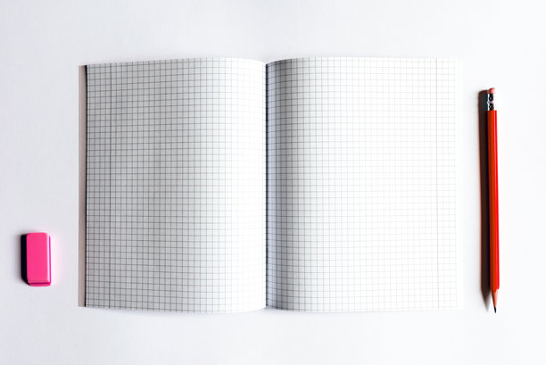 笔记本的俯视图照片，上面有格子页，上面有一支红色的铅笔和一块粉红色的橡皮。图片下载