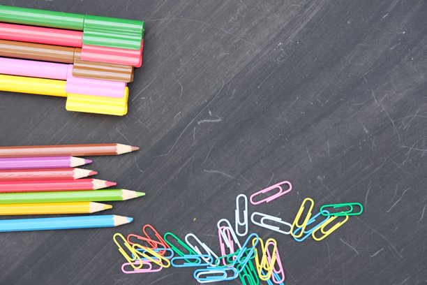 黑板上一排排形状各异的彩色铅笔。此图片适合用作壁纸和背景。彩色记号笔，彩色夹子，文具。图片下载
