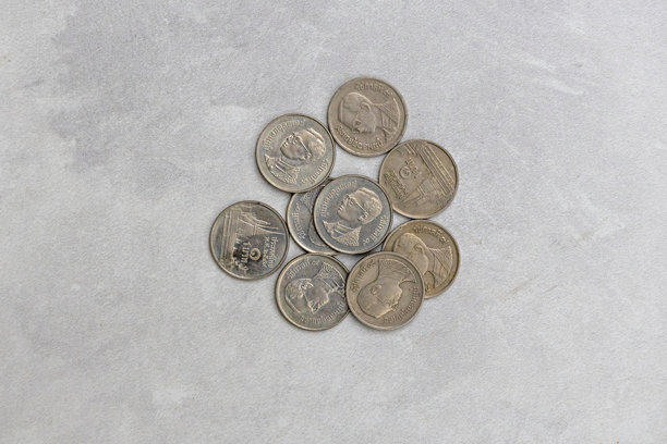 许多1986年至2008年的复古泰国1铢硬币散落在一起。正面展示了普密蓬·阿杜德国王（拉玛九世），背面则是曼谷的玉佛寺。历史货币。图片下载