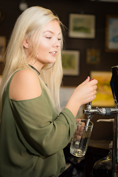 年轻女性在酒吧用龙头倒啤酒图片下载
