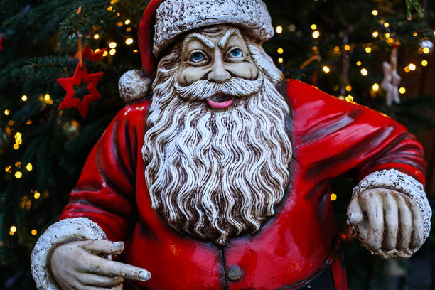 横向照片展示了一尊微笑的圣诞老人陶瓷雕塑，散发着圣诞气息。背景中有一棵圣诞树。图片下载