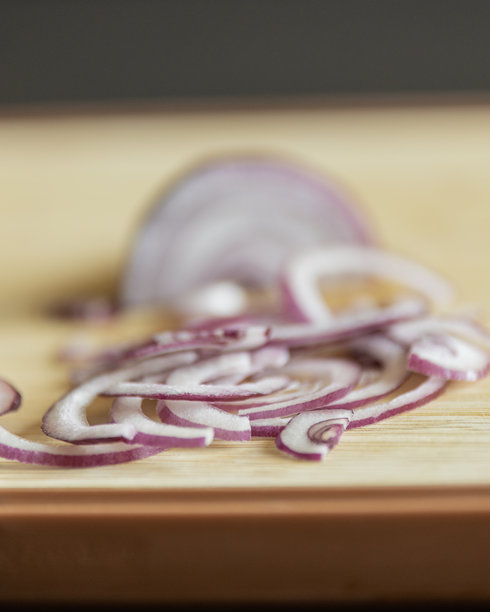 切好的紫洋葱特写照片，放在木质砧板上图片下载