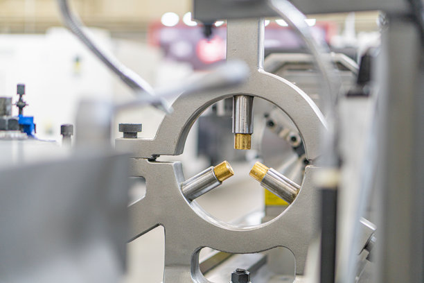 工业环境的特写照片，聚焦于一个具有四个对称突起部分的圆形金属组件，背景中充满了其他机械部件。图片下载