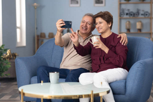 老年夫妇在家沙发上使用手机的照片图片下载