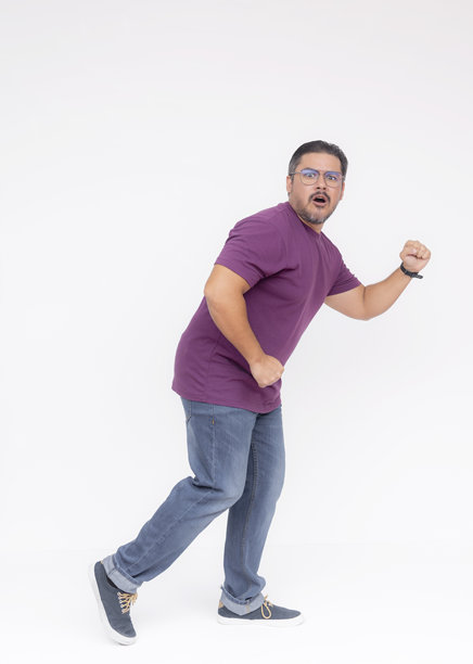 一个狡猾的中年胡子男人在被抓住时显得惊讶，正向右走。穿着紫色华夫格衬衫和牛仔裤。全身照片，背景为白色。图片下载