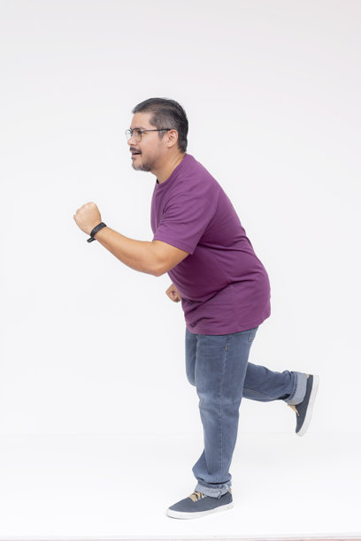 中年男子侧身奔跑，热切追赶，朝左侧移动。穿着紫色华夫格衬衫和牛仔裤。全身照片，背景为白色。图片下载