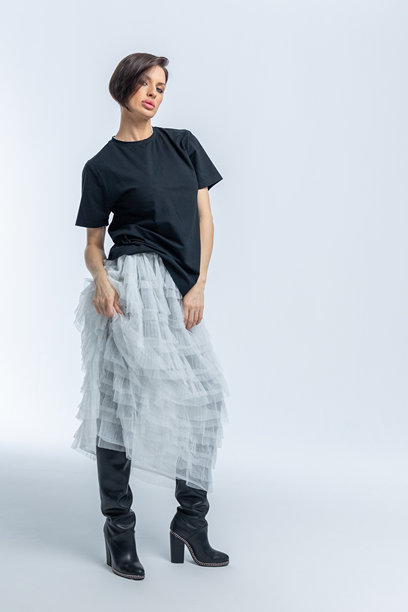 身穿黑色毛衣、浅灰色裙子的美丽模特，背景为白色。高端时尚。竖版照片。图片下载