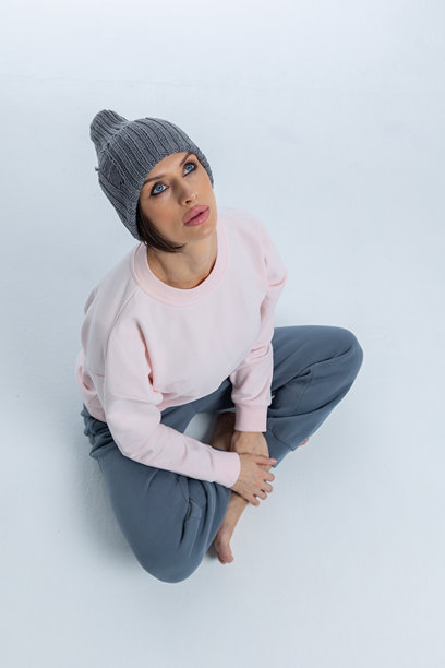 穿着灰色帽子的美丽女性肖像。女孩坐在地板上，双腿交叉。工作室摄影。竖版照片。图片下载