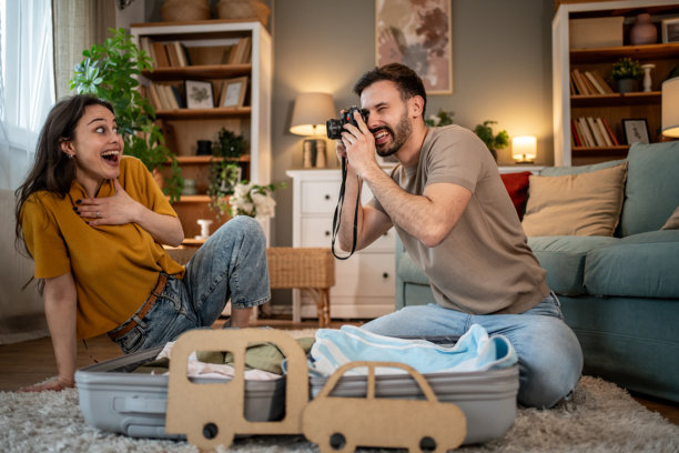 年轻情侣在打包公路旅行的行李并拍搞笑照片图片下载