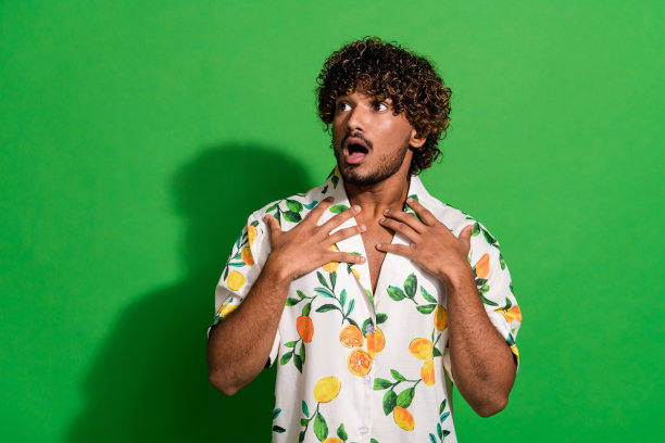照片中兴奋震惊的拉丁小伙穿着印花衬衫，张大嘴巴看着空旷孤立的绿色背景图片下载