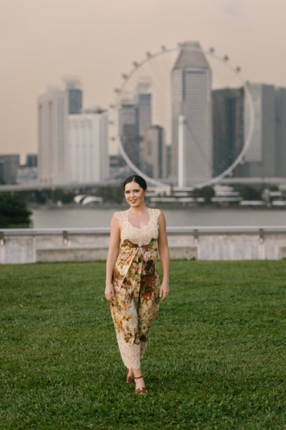 优雅的棕发女性，肤色浅，身材纤细，穿着花卉连衣裙在热带新加坡摆姿势。美学肖像，背景为郁郁葱葱的异国风情。图片下载