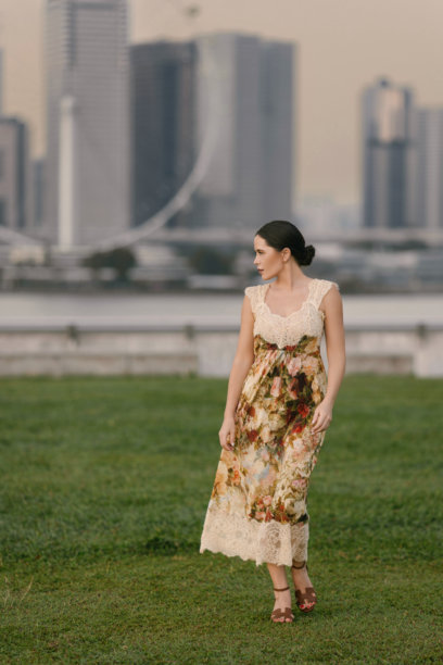 优雅的棕发女性，肤色浅，身材纤细，穿着花卉连衣裙在热带新加坡摆姿势。美学肖像，背景为郁郁葱葱的异国风情。图片下载