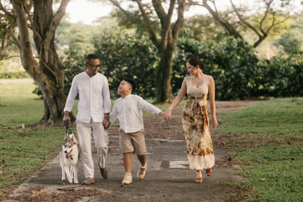 在新加坡拍摄的国际家庭照片，11岁的孩子微笑。亚洲父亲和儿子，白人母亲。郁郁葱葱的热带背景。图片下载