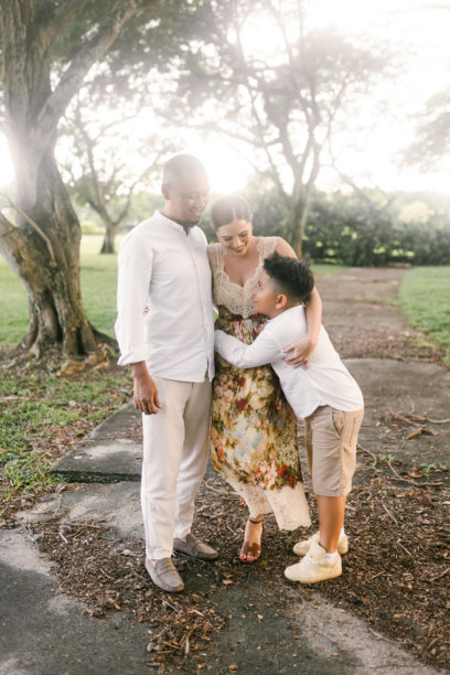 在新加坡拍摄的国际家庭照片，11岁的孩子微笑。亚洲父亲和儿子，白人母亲。郁郁葱葱的热带背景。图片下载