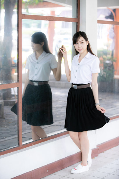 一位穿着整齐的亚洲女学生在大学制服中摆姿势，作为教职工照片拍摄的模特，展现出学术威望与现代优雅以及童真的自信。图片下载