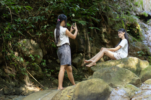 雅加达的印尼亚洲女性在瀑布前拍摄旅行照片图片下载