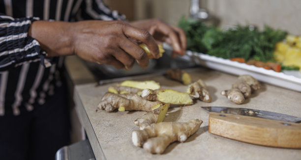 泡茶。一个非裔美国女性正在切姜以制作传统草药茶。特写照片，仅显示手部。图片下载