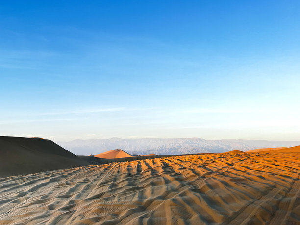 美丽的沙丘在沙漠的日出日落时分。干旱的风景中，沙子上留下了越野车的轮胎轨迹，带着游客来到秘鲁伊卡的华卡奇纳沙漠地区。图片下载