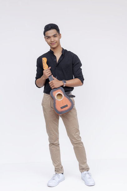 一位年轻帅气、穿着考究的男士手持尤克里里。全身照片，背景为白色。图片下载