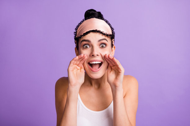 女孩在淡紫色背景下，双手靠近脸庞，低声讲述秘密信息的照片肖像图片下载