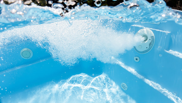 游泳池中强劲水流的水下照片，水流在池壁附近形成气泡和涡流，清澈的蓝色水面和光线反射。图片下载