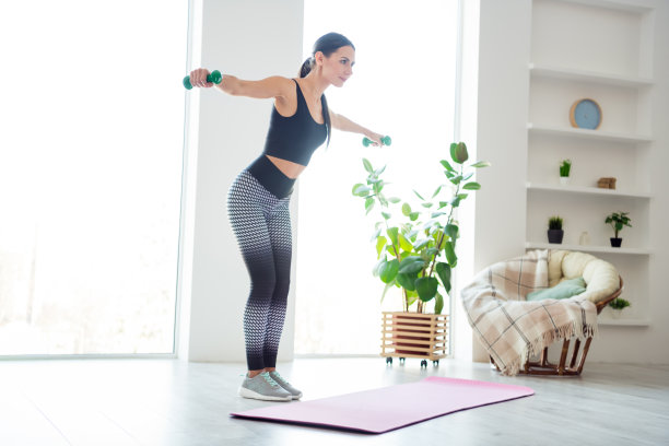 美丽女士全身侧面照片，双手举起哑铃，早晨在室内进行肩部训练。图片下载