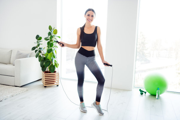 全身照片，快乐积极、迷人的女孩在家中跳绳锻炼。图片下载