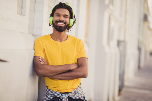 自信的男子在街上微笑着，双手交叉，戴着耳机听音乐的照片肖像图片下载