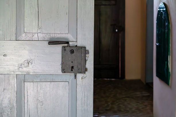 一扇带金属锁的旧木门通向传统建筑的内部。可见走廊，地面为石材，装饰元素具有复古风格。图片下载