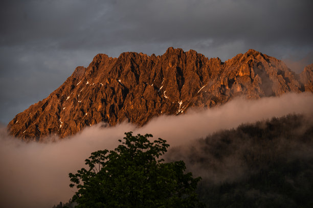 金色时光的山峰：沐浴在光线中的戏剧性山脉，笼罩在雾气中 – 阿尔卑斯的壮丽库存照片图片下载